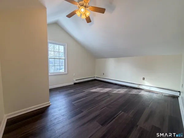 an empty room with wooden floor chandelier fan and windows