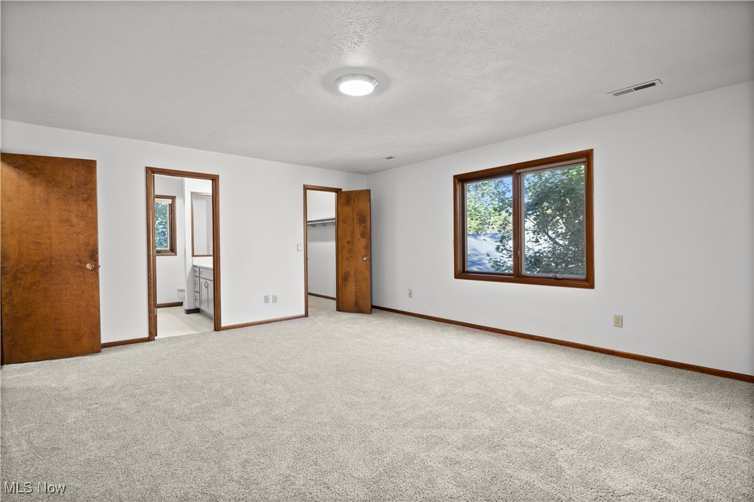 1711 Gulf Road Elyria, OH 44035 - Photo 27 of 50 Unfurnished bedroom featuring a spacious closet, light carpet, a textured ceiling, and ensuite bathroom