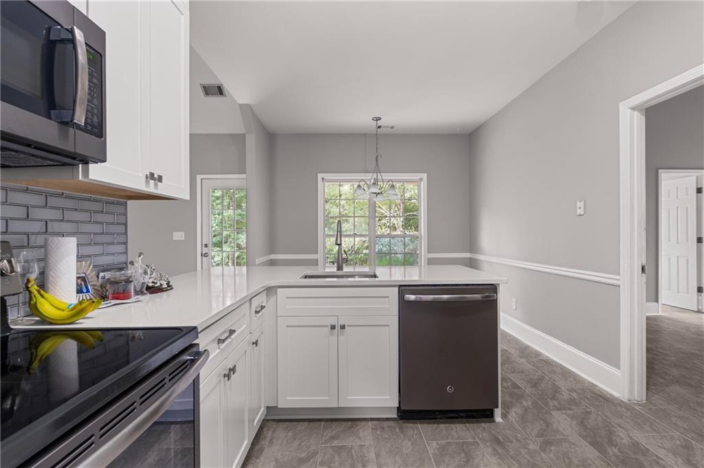 1449 Cummings Road Smiths Station, AL 36877 - Photo 17 of 28 Kitchen featuring white cabinetry, light-toned countertops, a stainless steel microwave, and a dark-finish dishwasher