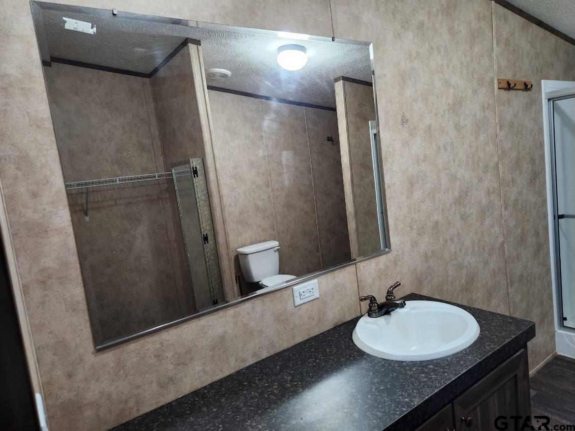 6339 Gorilla Road Gilmer, TX 75644 - Photo 4 of 12 a bathroom with a granite countertop sink toilet and shower