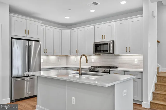 a kitchen with stainless steel appliances granite countertop a refrigerator stove a sink and white cabinets