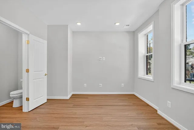 a view of an empty room with wooden floor and windows