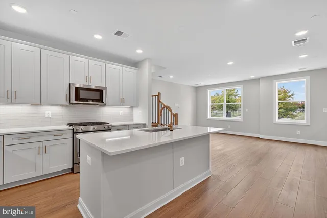 a kitchen with stainless steel appliances granite countertop a stove a sink and a microwave