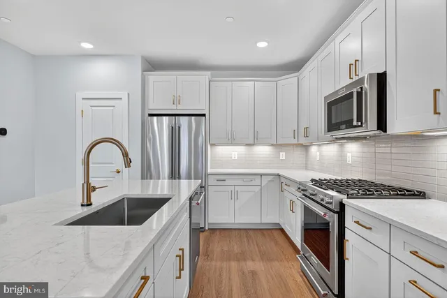 a kitchen with granite countertop a sink stainless steel appliances and cabinets