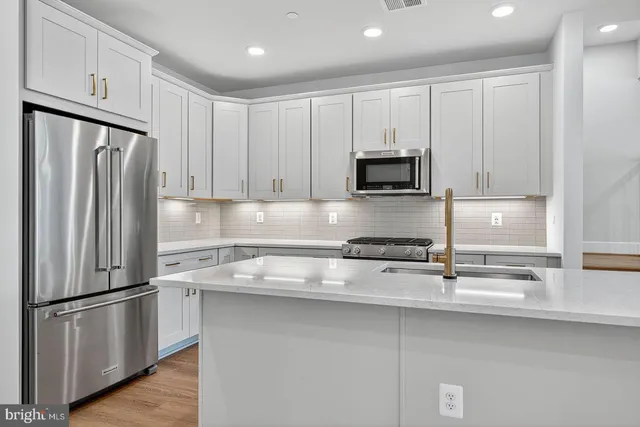 a kitchen with stainless steel appliances granite countertop a refrigerator a stove a sink and a microwave