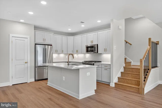 a kitchen with stainless steel appliances granite countertop a refrigerator and a stove top oven