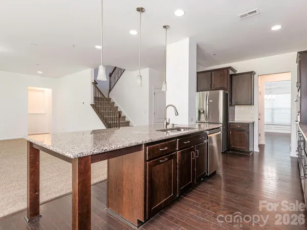 a kitchen with stainless steel appliances granite countertop a sink a stove and a wooden floors