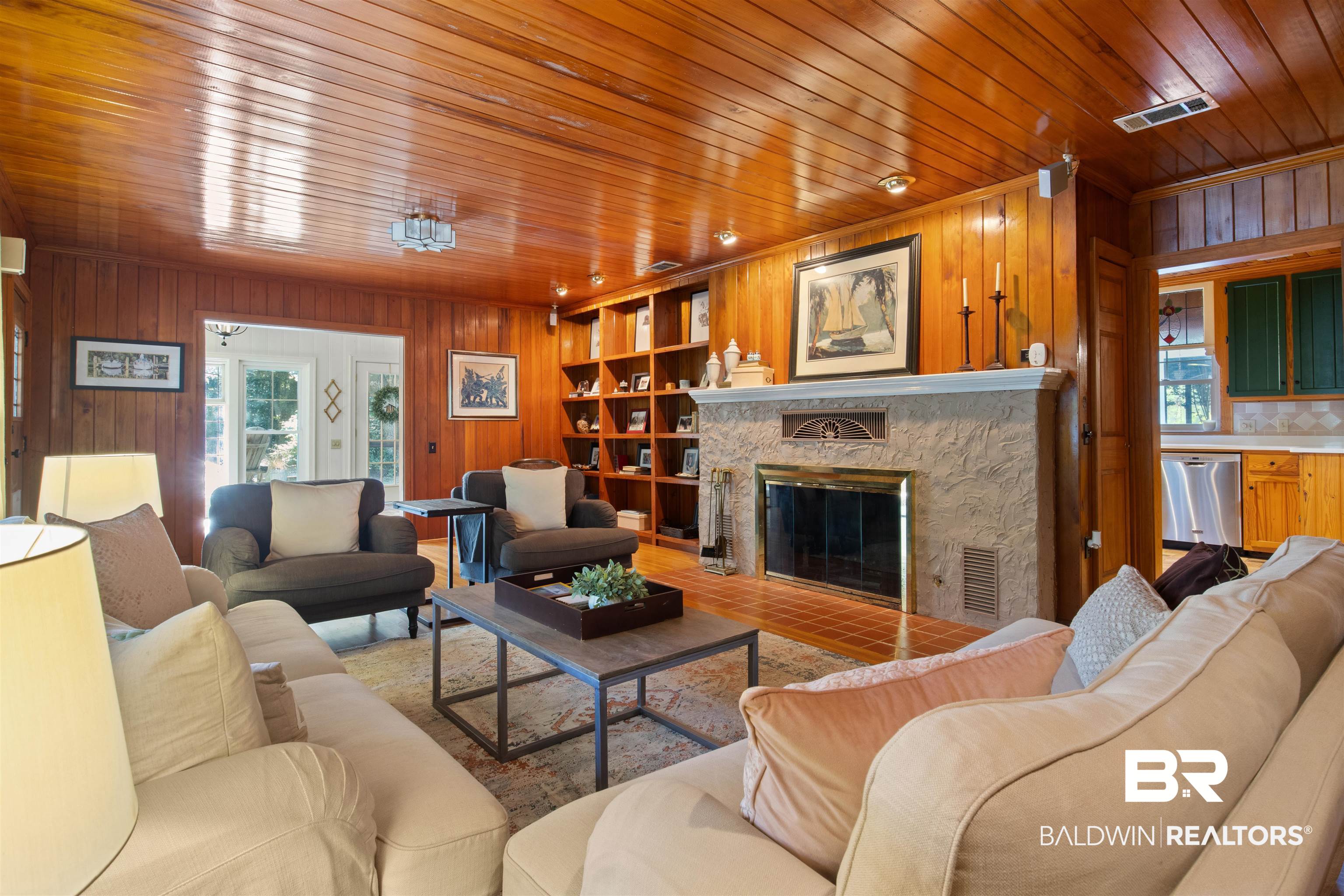 15100 Vasko Road Silverhill, AL 36576 - Photo 20 of 51 Living room with wood ceiling, a stone fireplace, and wooden walls. Built in book shelves provide display for photos, collections, record player or bar area.