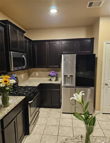 a kitchen with granite countertop a refrigerator and a stove top oven
