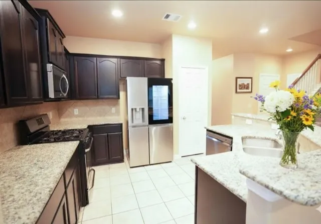 a kitchen with kitchen island granite countertop a sink and refrigerator