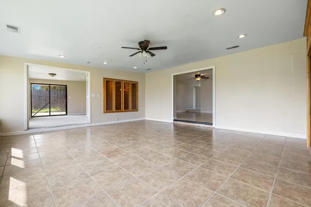 an empty room with windows and fan