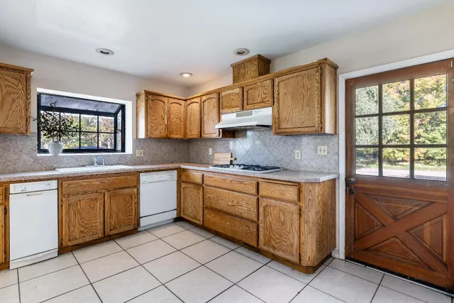 a kitchen with granite countertop a refrigerator and a stove top oven
