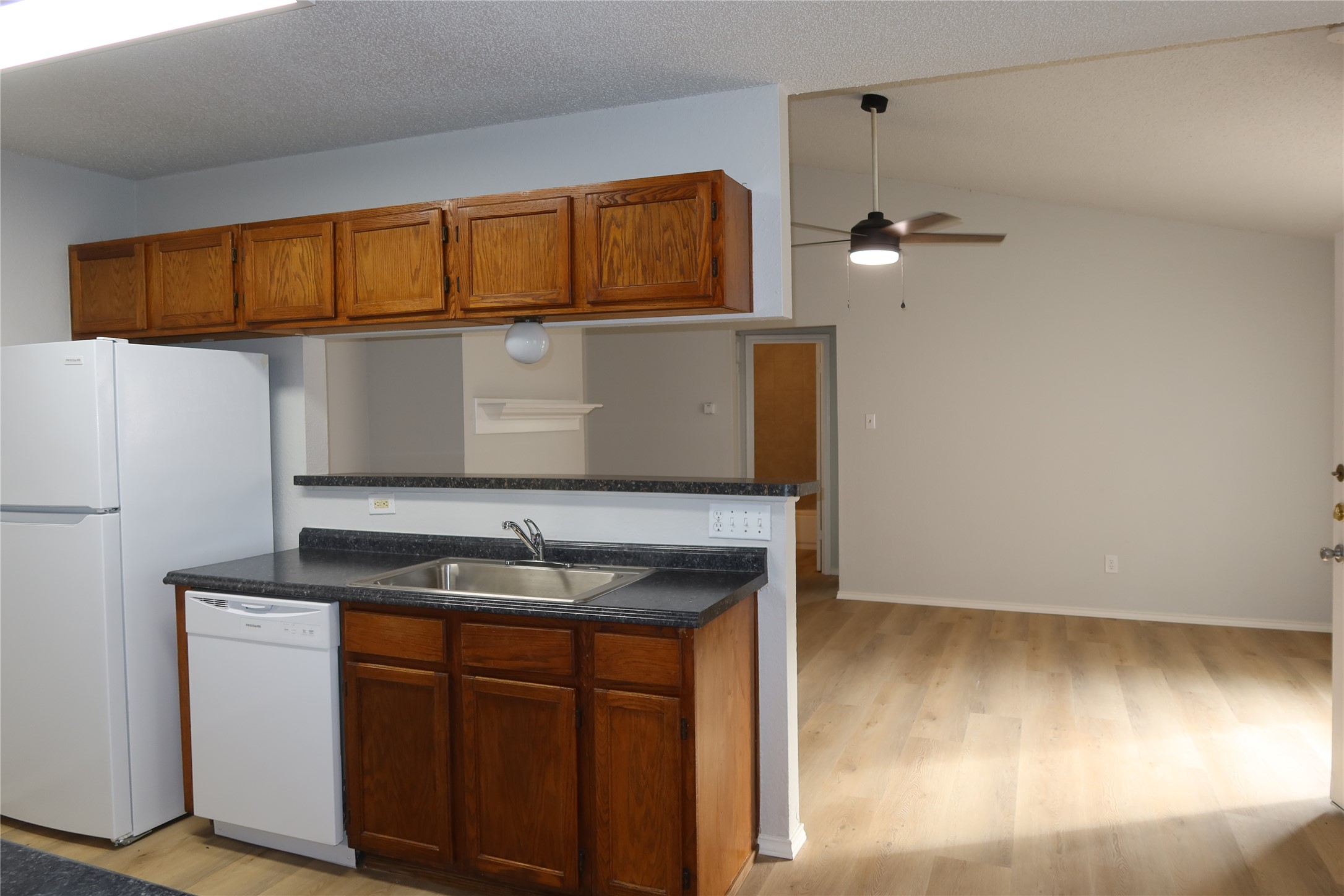 2511 Bucks Run, Unit A Austin, TX 78744 - Photo 4 of 25 Kitchen with light wood-style floors, dark countertops, ceiling fan, and wood finish cabinetry