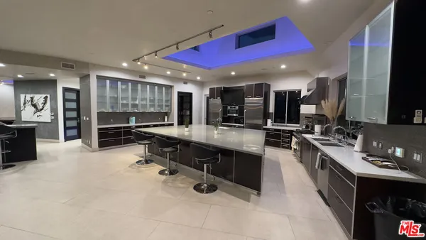 a kitchen with stainless steel appliances kitchen island granite countertop a sink counter space and a view of living room