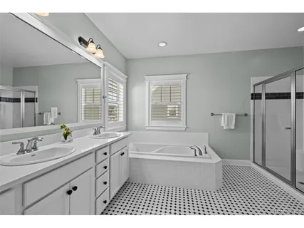 a spacious bathroom with a double vanity sink a mirror and a bathtub