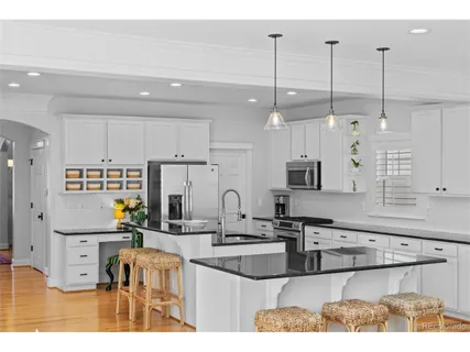 a kitchen with stainless steel appliances granite countertop a refrigerator a stove top oven a sink dishwasher and white cabinets with wooden floor