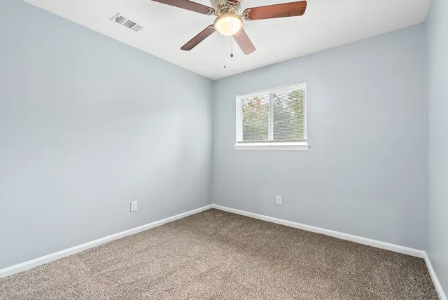 an empty room with a window and a fan