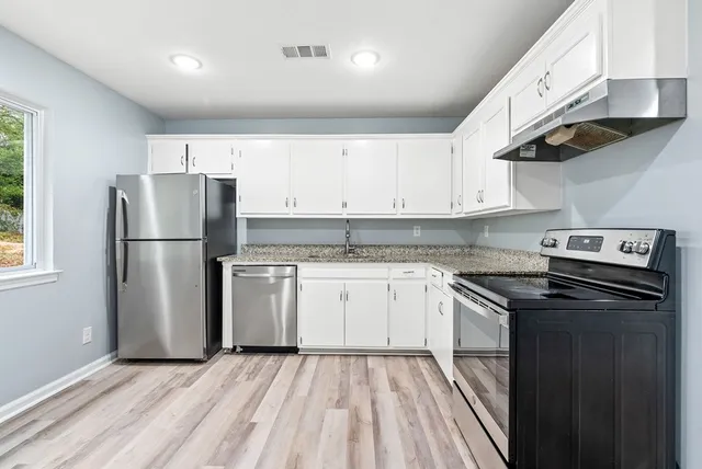 a kitchen with granite countertop a refrigerator stove and sink