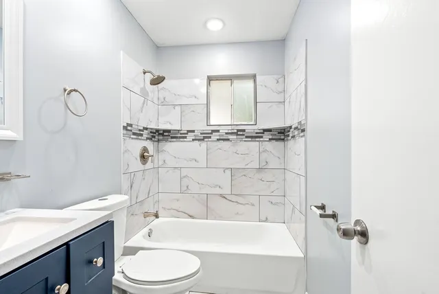 a bathroom with a bathtub shower sink vanity and toilet