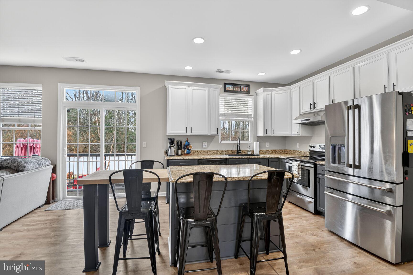 1409 James Way Edgewater, MD 21037 - Photo 5 of 21 a kitchen with stainless steel appliances granite countertop a stove a refrigerator a kitchen island and chairs in it