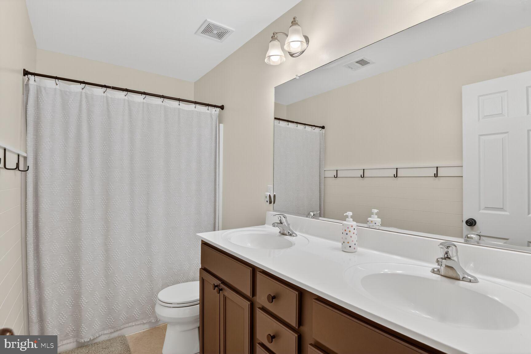 1409 James Way Edgewater, MD 21037 - Photo 10 of 21 a bathroom with a double vanity sink toilet and a mirror