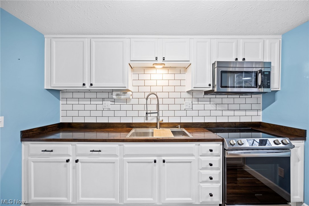 4251 Kenneth Road Stow, OH 44224 - Photo 6 of 19 Kitchen with sink, a textured ceiling, electric stove, white cabinetry, and backsplash