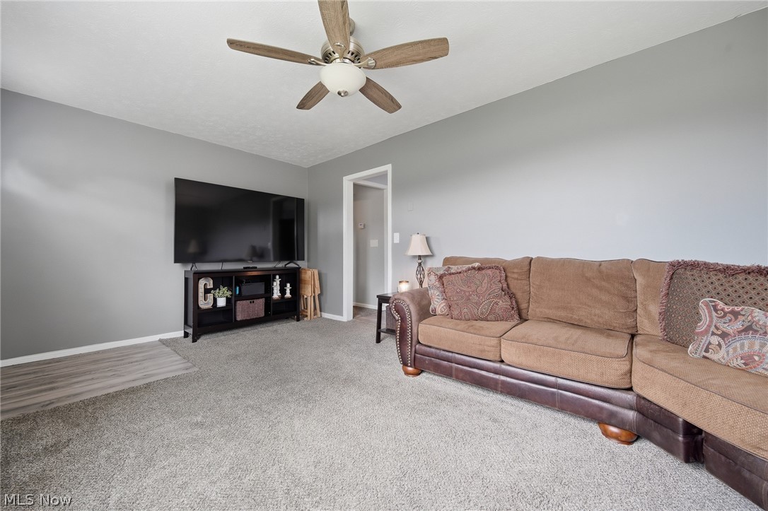 3471 State Rte 5 Newton Falls, OH 44444 - Photo 5 of 31 Carpeted living area with light gray walls, a ceiling fan with integrated lighting, and a wood-finish flooring section