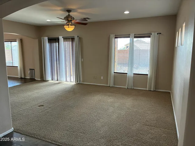 an empty room with ceiling fan and windows