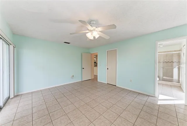 an empty room with windows and ceiling fan
