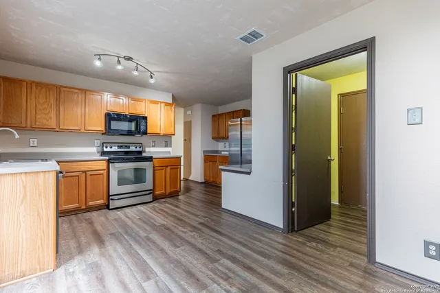 a kitchen with stainless steel appliances kitchen island wooden cabinets and a refrigerator