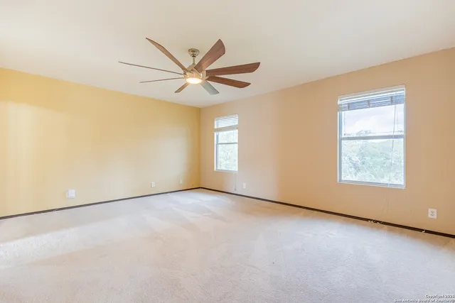 an empty room with windows and fan