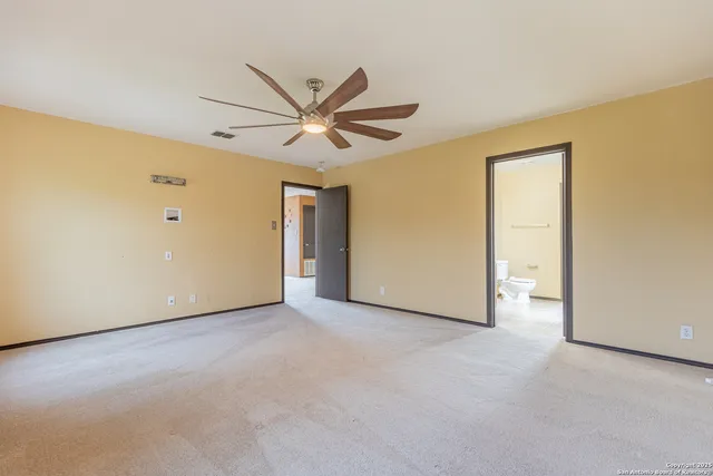 a view of an empty room with closet and a ceiling fan