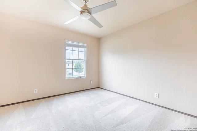 an empty room with a window and a fan