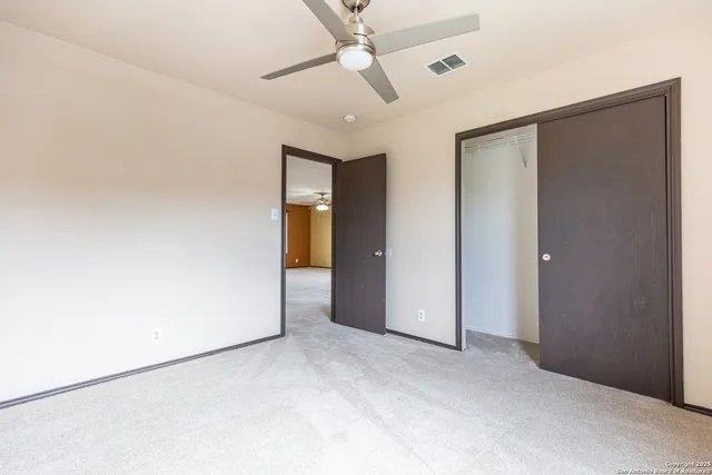 an empty room with closet and a ceiling fan