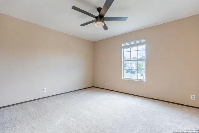 an empty room with a window and a fan