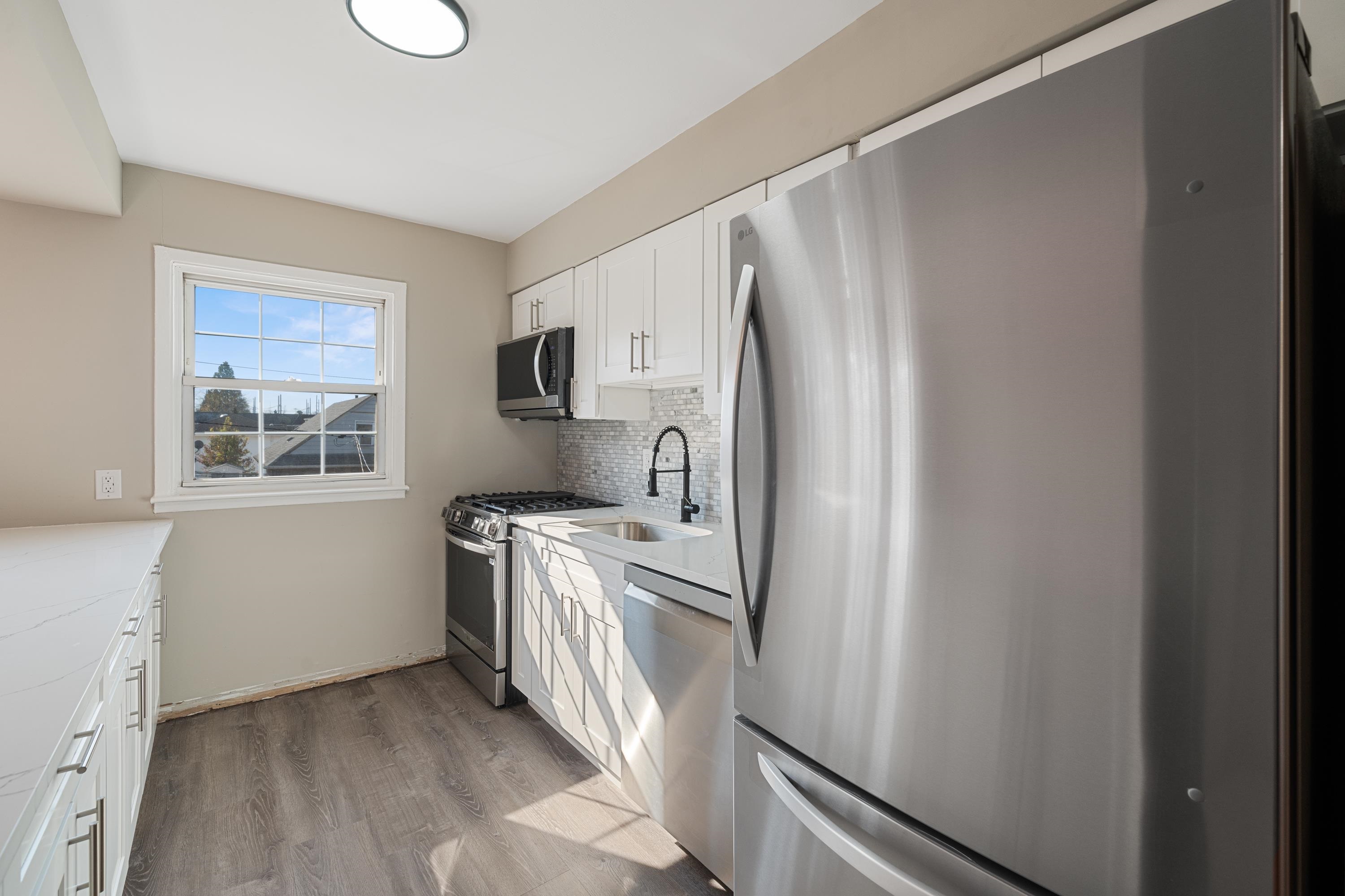 14 Delmar Road Jersey City, NJ 07305 - Photo 10 of 38 a kitchen with stainless steel appliances a refrigerator a stove a sink and a window