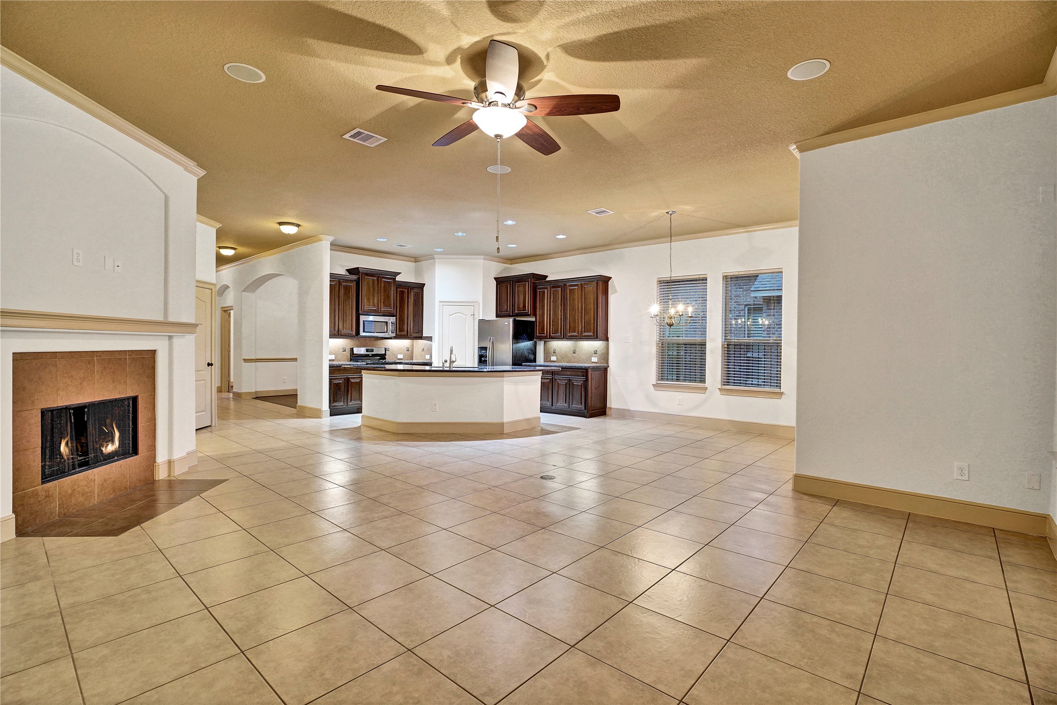 10 Tallgrass Way Spring, TX 77389 - Photo 8 of 23 a view of a livingroom with a fireplace a ceiling fan and kitchen view