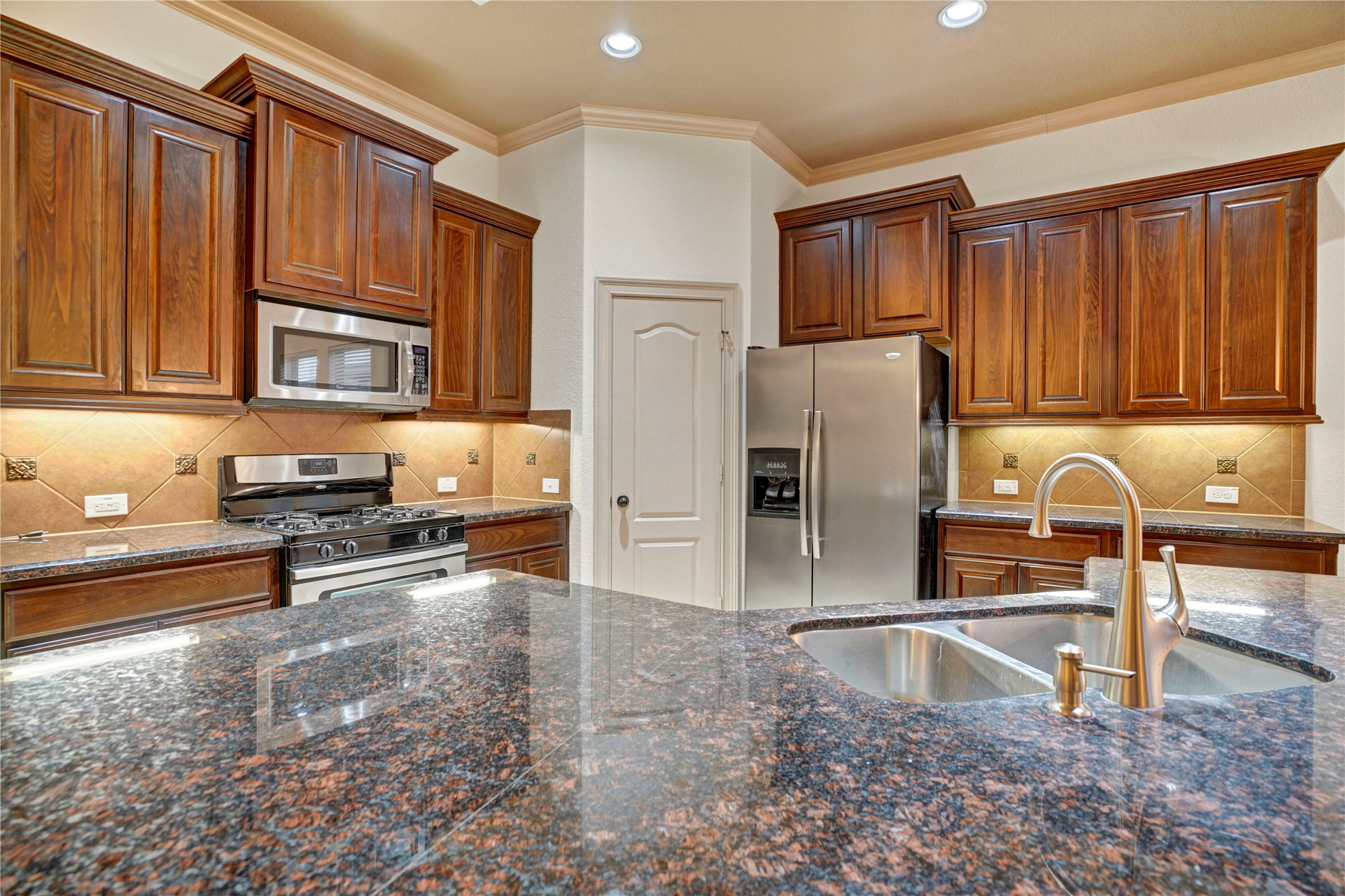 10 Tallgrass Way Spring, TX 77389 - Photo 10 of 23 a kitchen with granite countertop wooden cabinets a refrigerator and a sink