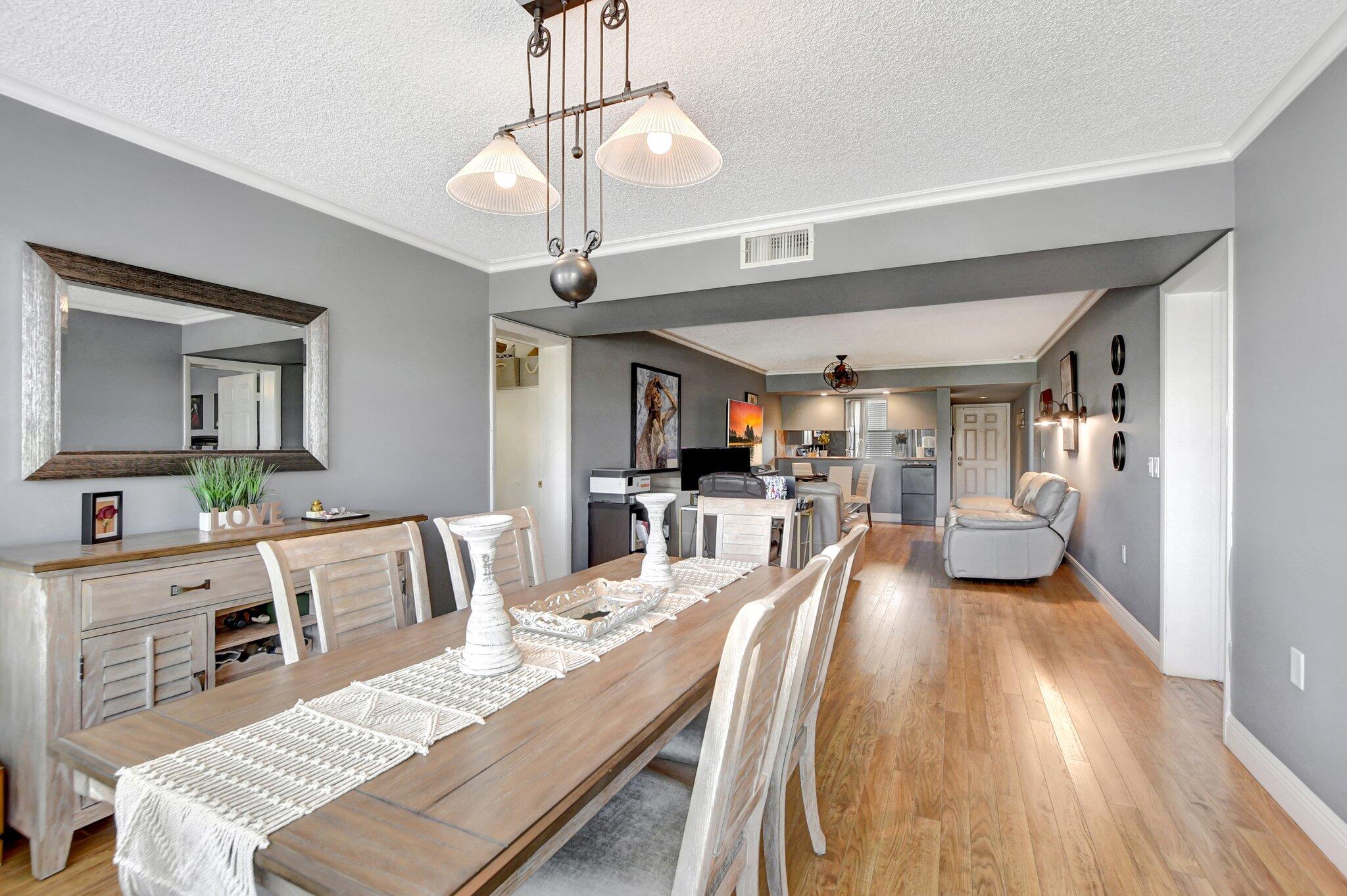 6025 Balboa Circle, Unit 303 Boca Raton, FL 33433 - Photo 9 of 23 a view of a dining room and livingroom with furniture wooden floor a chandelier