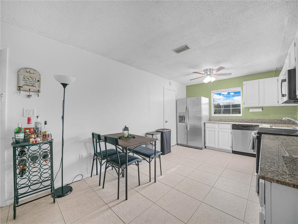525 South Conway Road, Unit 100 Orlando, FL 32807 - Photo 9 of 23 a kitchen with stainless steel appliances kitchen island granite countertop a table and chairs in it