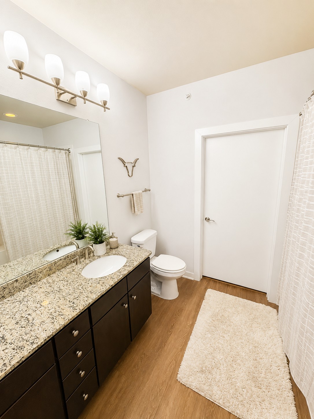 1900 Barton Springs Road, Unit 3036 Austin, TX 78704 - Photo 6 of 19 A well-appointed bathroom features a dark wood vanity and speckled granite counters, illuminated by modern vanity lighting.