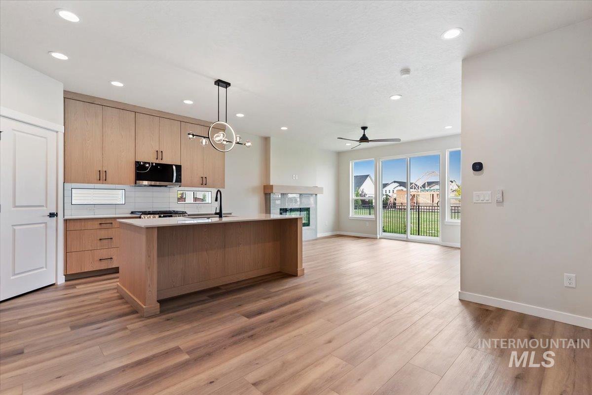 3866 West Spring House Lane Eagle, ID 83616 - Photo 33 of 33 Kitchen with decorative light fixtures, an island with sink, backsplash, open floor plan, and recessed lighting