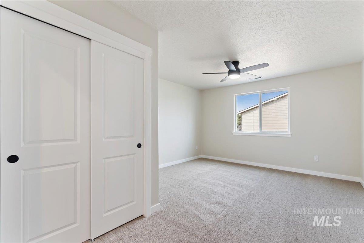 3866 West Spring House Lane Eagle, ID 83616 - Photo 13 of 33 Unfurnished bedroom featuring light carpet, a closet, a textured ceiling, and a ceiling fan