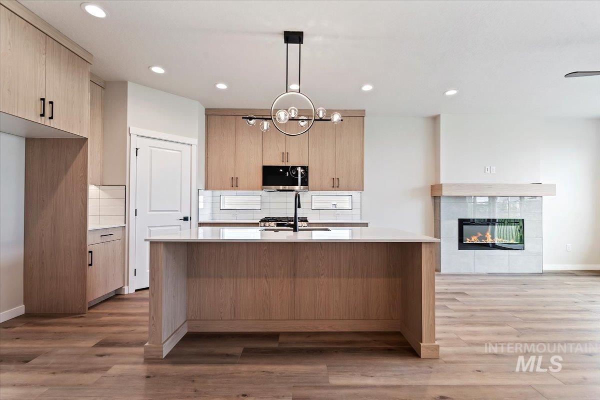 3866 West Spring House Lane Eagle, ID 83616 - Photo 8 of 33 Kitchen featuring backsplash, light stone countertops, light brown cabinets, a fireplace, and recessed lighting