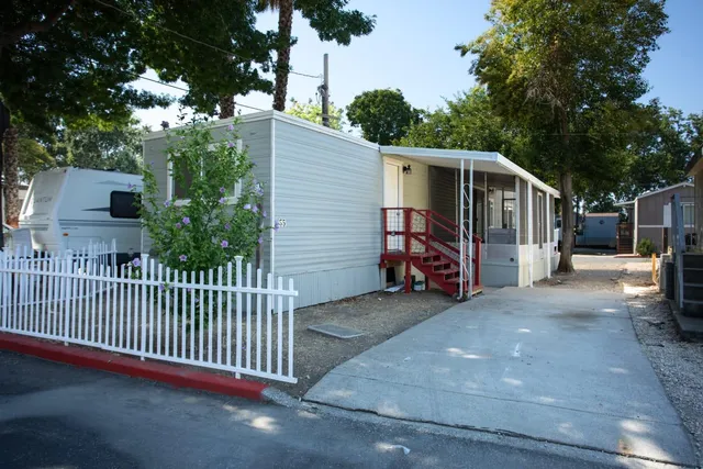 a view of a house with a small yard and large trees