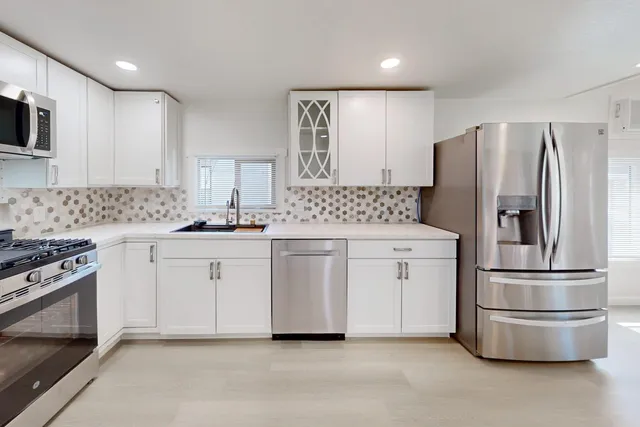 a kitchen with white cabinets and stainless steel appliances