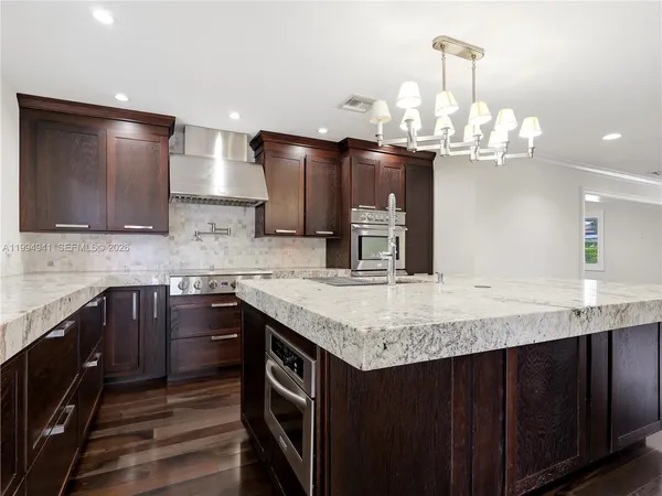 a kitchen with kitchen island granite countertop a sink and dishwasher with wooden floor