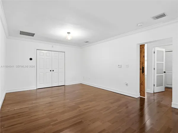 a view of an empty room with wooden floor and a window