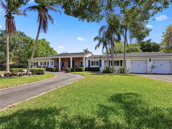 a front view of a house with a garden and lake view