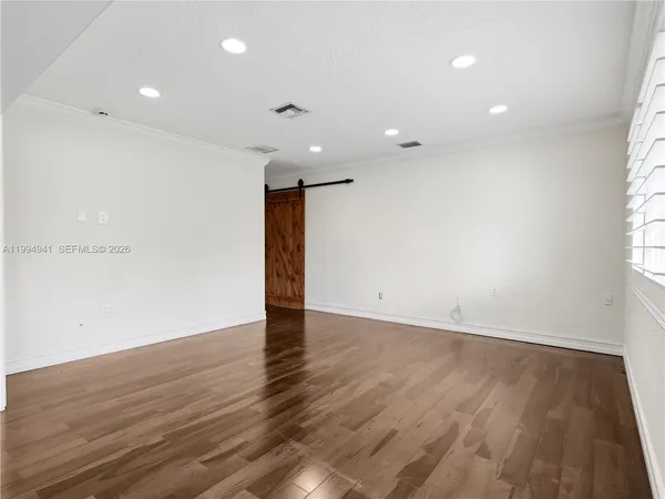 a view of an empty room with wooden floor and a window